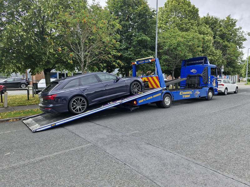 Camel Tow flatbed loading a dark grey Audi — CAMEL TOW and phone number on the truck