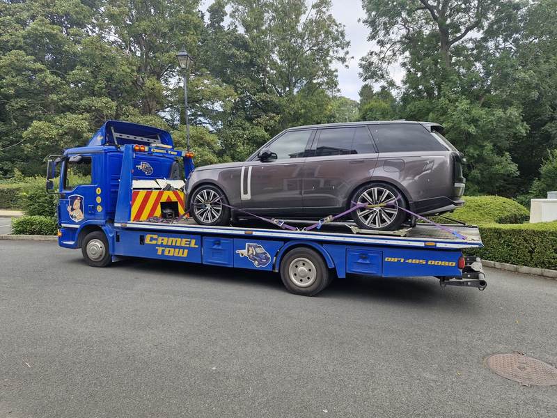 Range Rover secured with purple straps on a blue Camel Tow flatbed