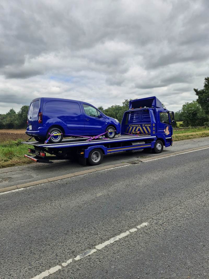 Blue van recovered onto a Camel Tow flatbed on a rural roadside